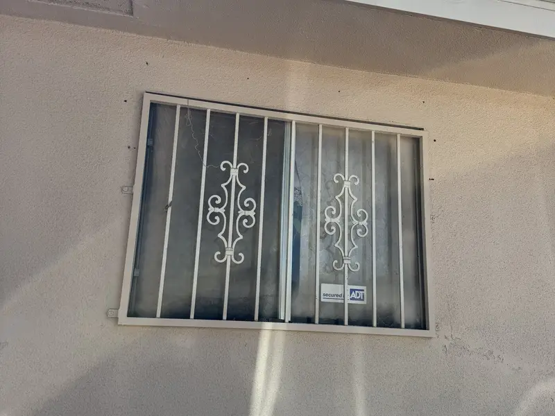 Old single-pane window with security bars before replacement
