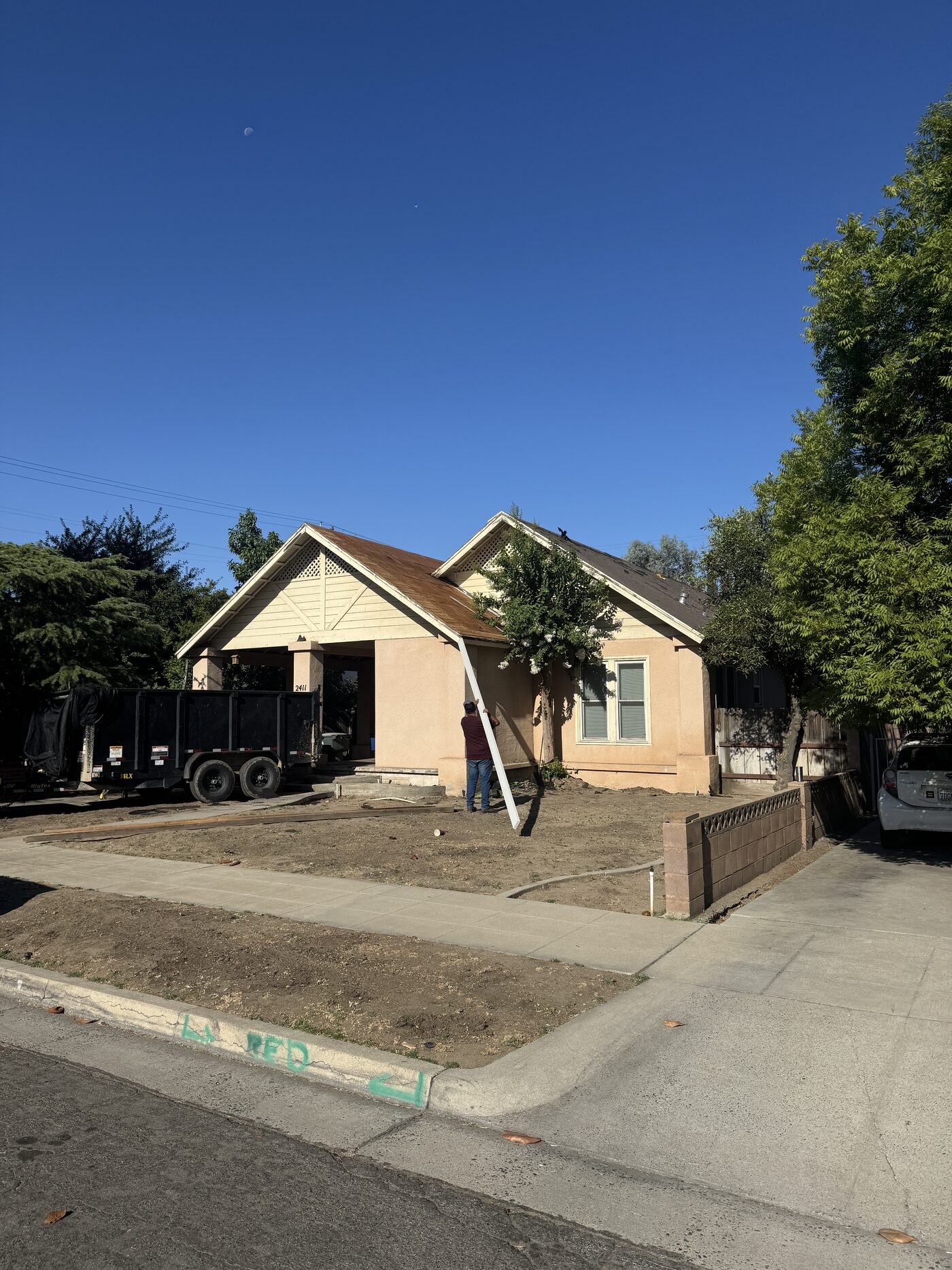Before: the Fresno home with its aging roof on day one, dumpster trailer staged for tear-off