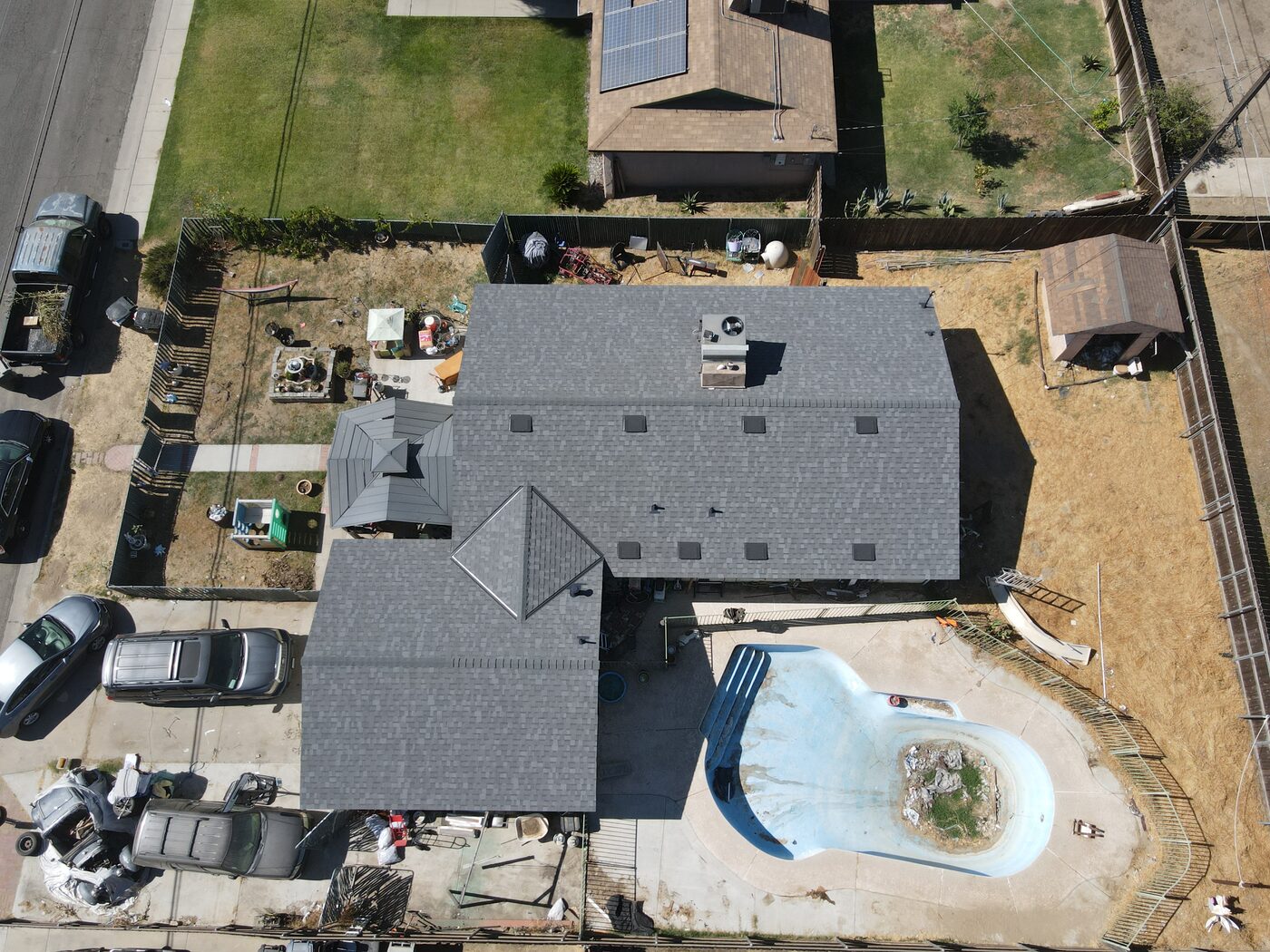 Completed shingle roof on a Hanford, CA home with a backyard pool, aerial view